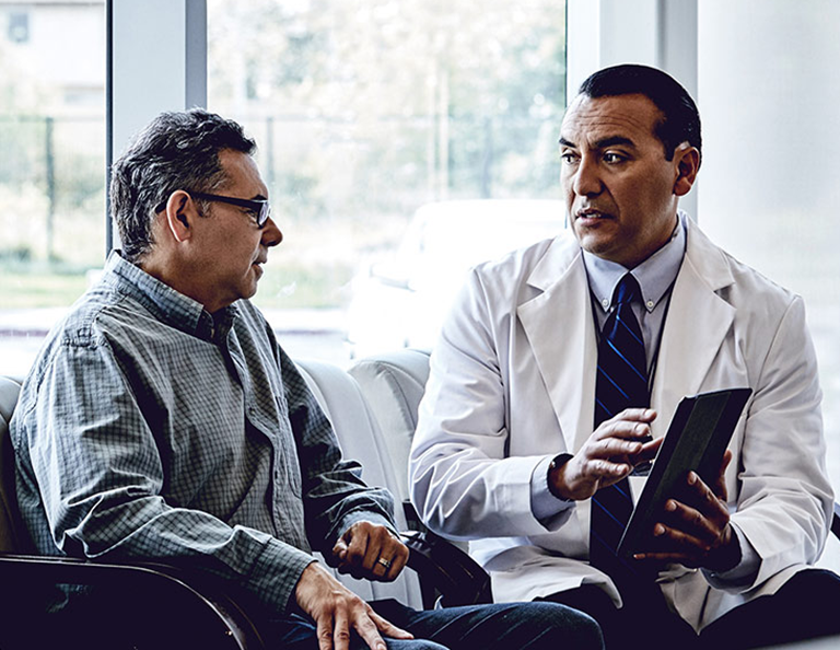 Doctor-with-digital-tablet-discussing-with-male-patient-in-waiting-room