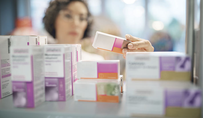 female pharmacist checking medicines in foreground