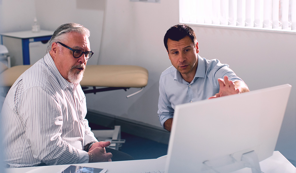 Male-doctor-meeting-with-senior-patient-at-computer-768×594