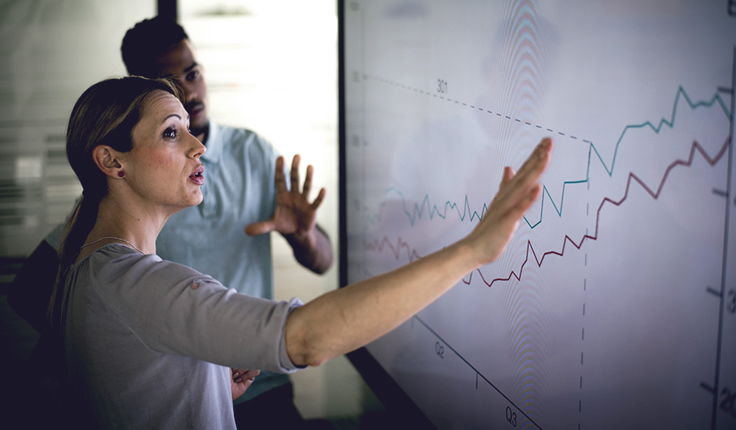 Man and woman reviewing data on large screen