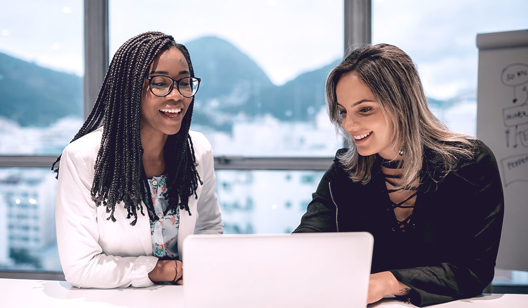 Two women looking at laptop on table